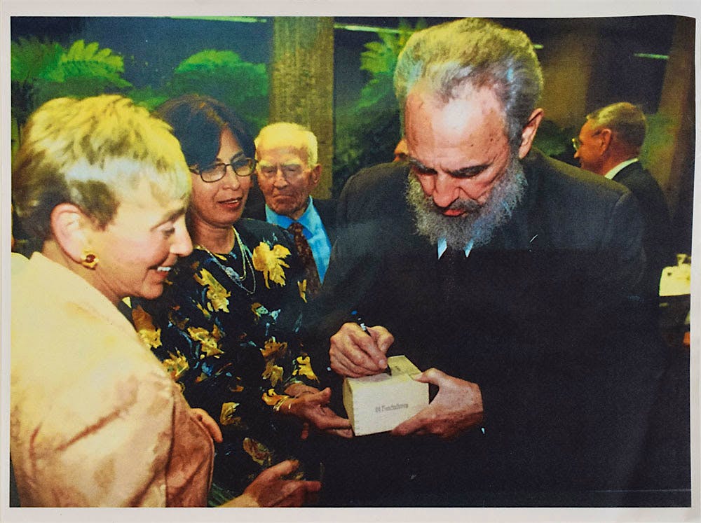 Castro, right, signing the box of Trinidads before presenting it to philanthropist Dr. Eva Haller, left.